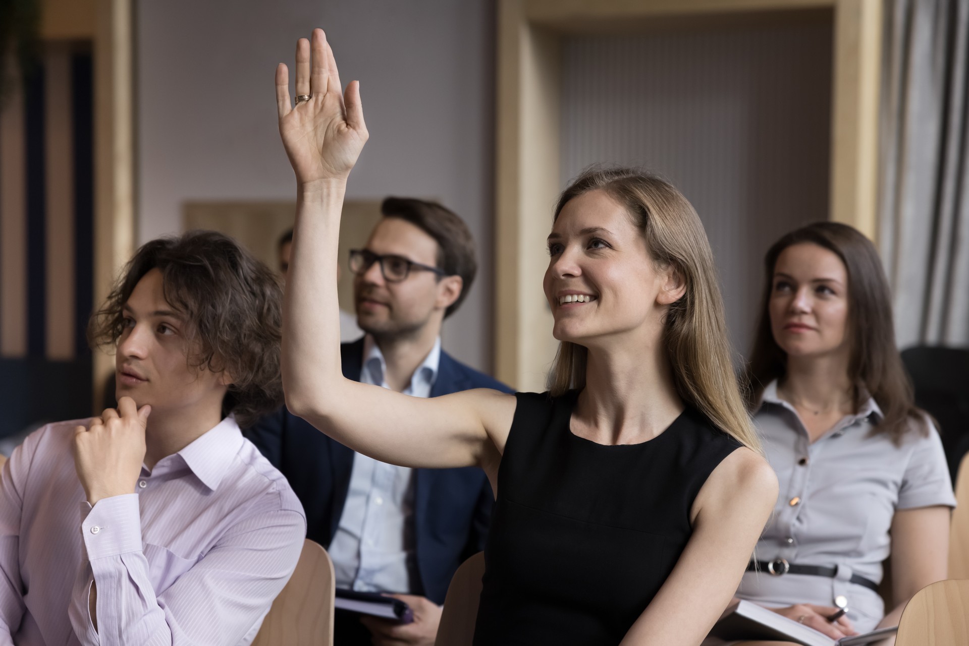 Smiling businesswoman raise arm to ask question engaged educational seminar